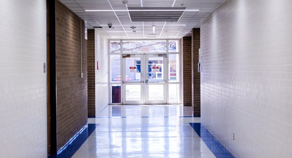 Wide and bright school hallway with glass exit doors leading outside, creating a welcoming atmosphere.